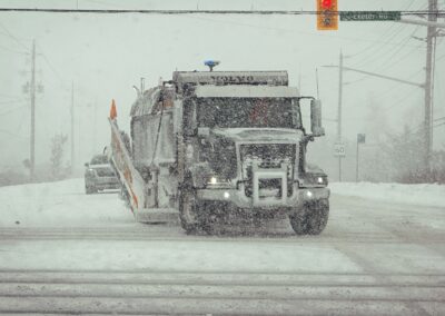 S & B Services dump truck with snow plow driving in a snow storm