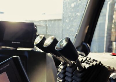 Interior cab view of a winter maintenance truck showing a multi-light camera monitor mount, joystick controls, and spreader display screens.